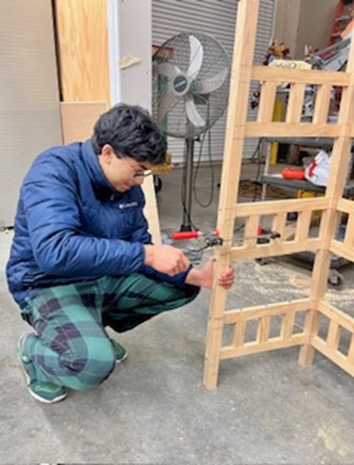 Aman working on assembling the wooden utility cart